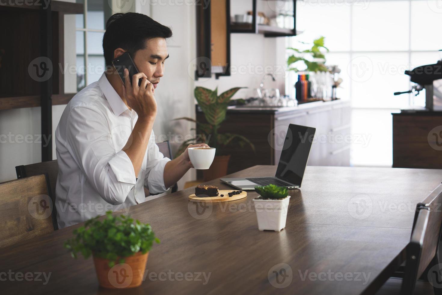 uomo asiatico seduto al bar, bevendo caffè e colazione, svegliandosi in lontananza. concetto di business e tecnologia foto