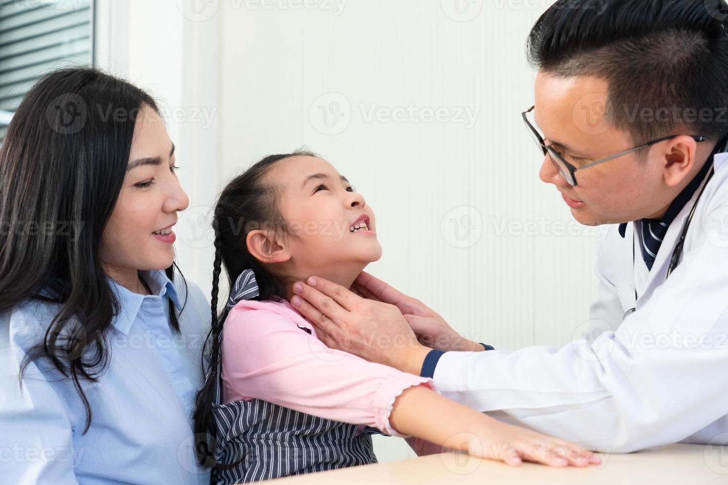 medico asiatico palpa i linfonodi cervicali al collo della ragazza che ha mal di gola e visita alla clinica ospedaliera. concetto di assistenza sanitaria e medica foto