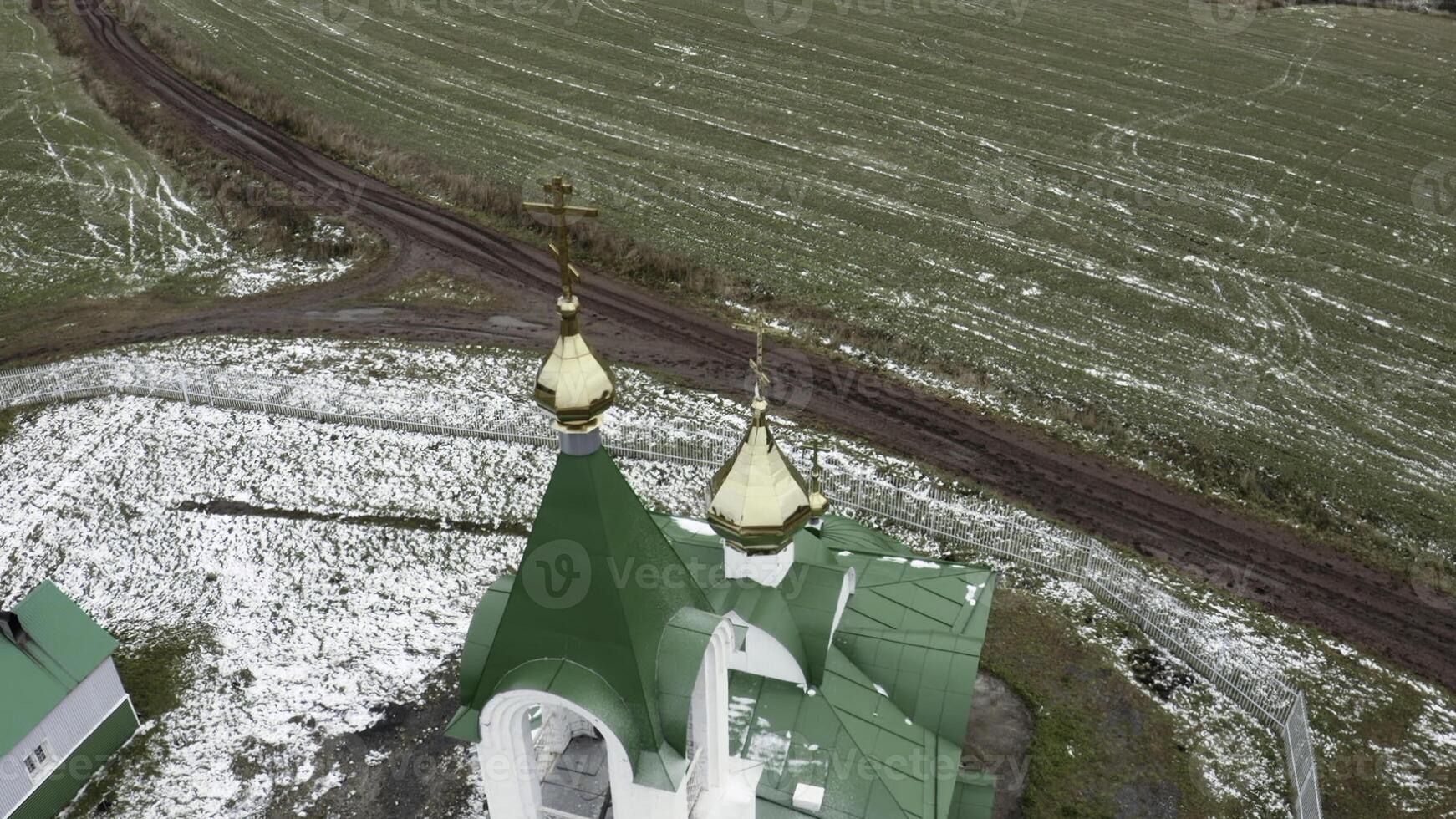 aereo Visualizza di un' Chiesa con verde tetto e d'oro cupole. clip. Chiesa circondato di verde azienda agricola i campi nel presto primavera. foto