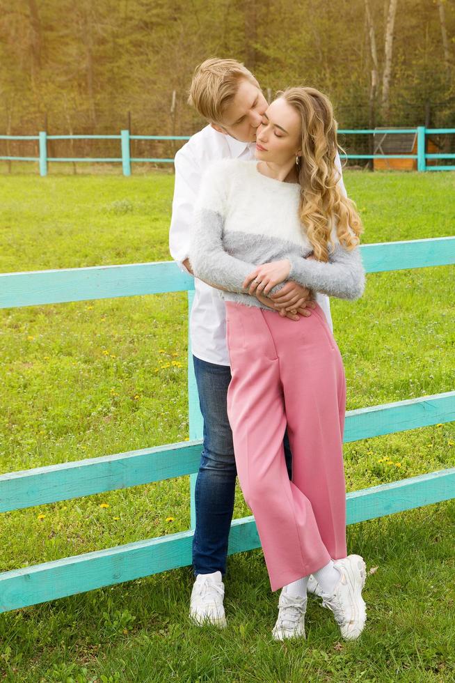 bella coppia si abbraccia sull'erba verde, lui la bacia foto