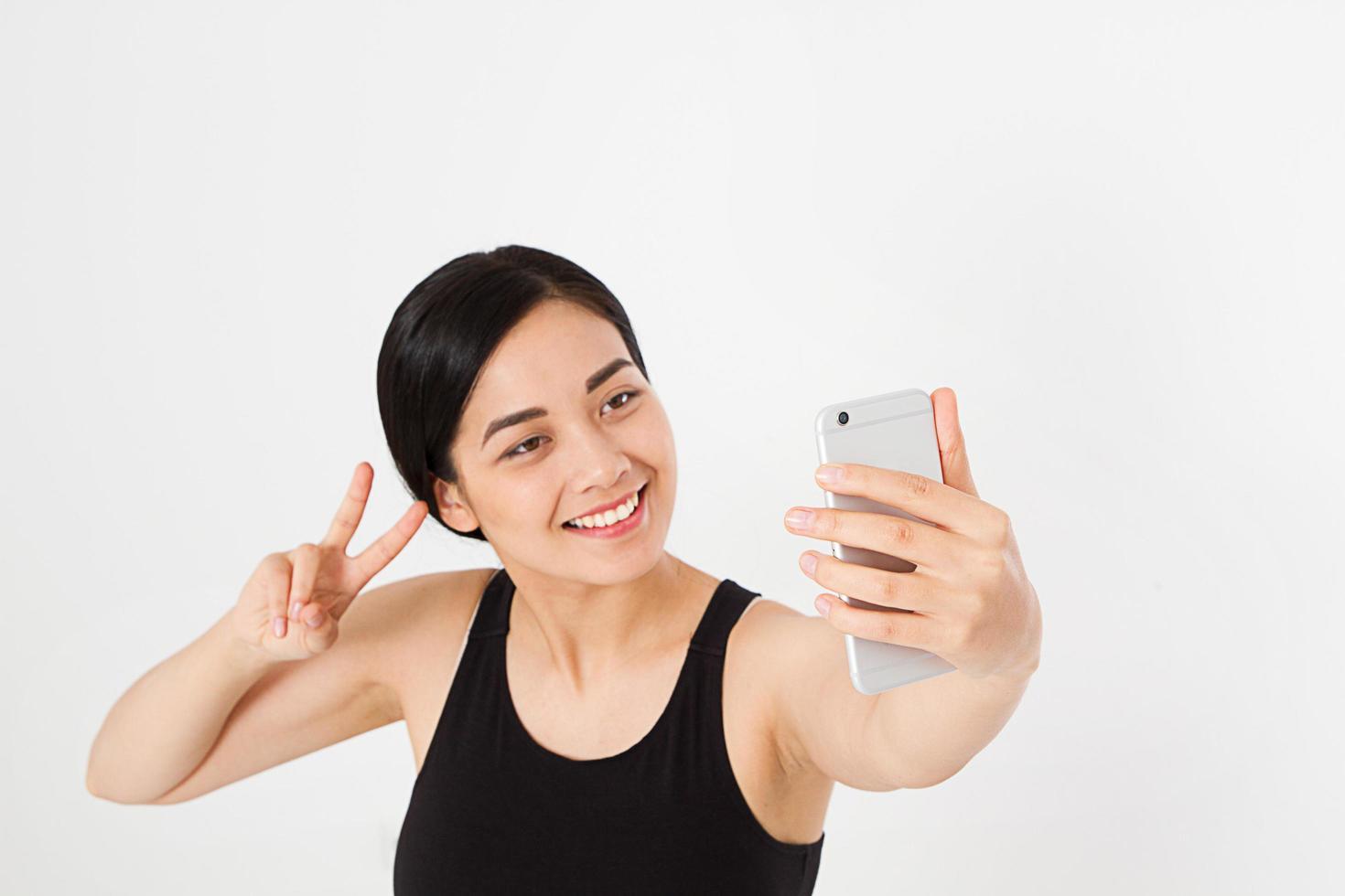 sexy, bella asiatica, donna coreana che prende un selfie e mostra la vista della pace o della vittoria isolata su sfondo bianco, copia spazio, mock up foto