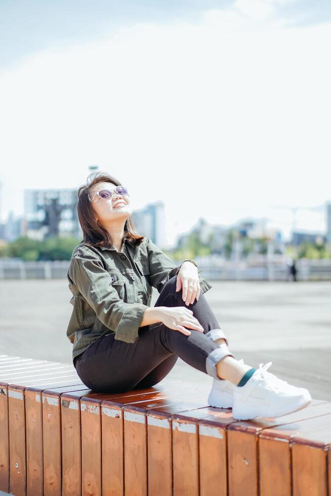 giovane bellissimo asiatico donna indossare giacca e nero jeans in posa all'aperto foto