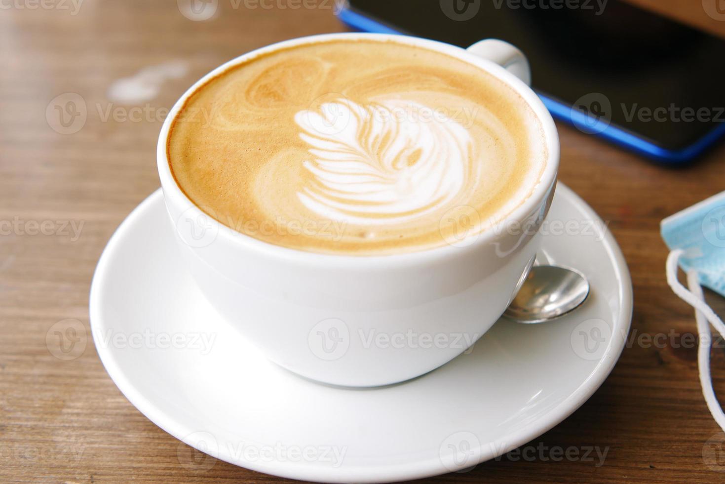 una tazza di caffè in ritardo con un design a forma di fiore in cima al bar foto