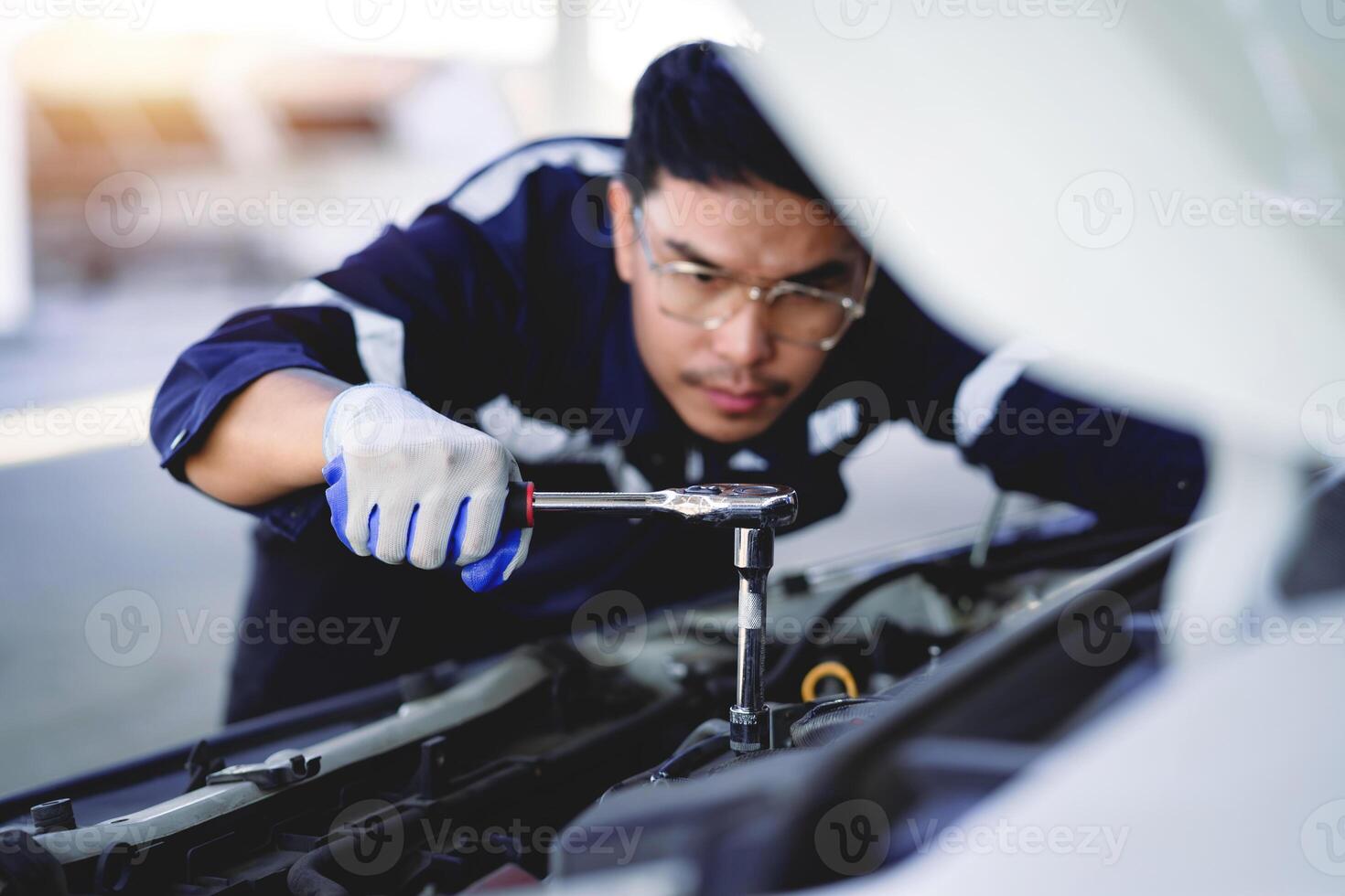 auto meccanico è Lavorando su auto motore nel meccanico negozio. un' meccanico nel uniforme è Lavorando su un' auto servizio. opera nel riparazione negozi e Manutenzione Servizi. foto