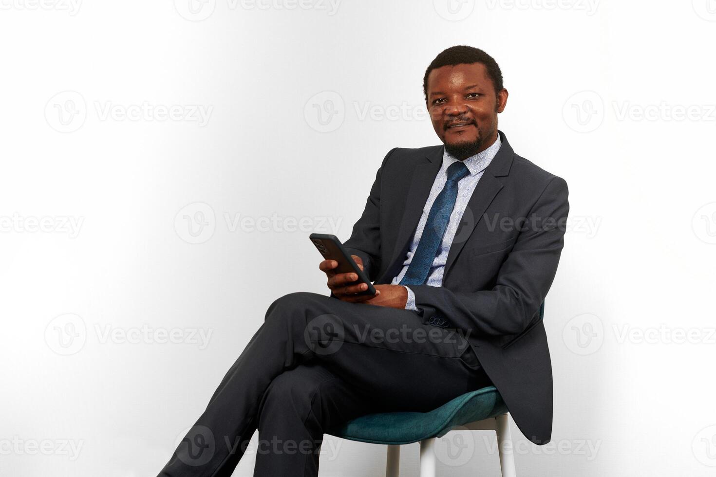 sorridente africano americano nero uomo nel attività commerciale completo da uomo seduta su sedia isolato su bianca sfondo foto