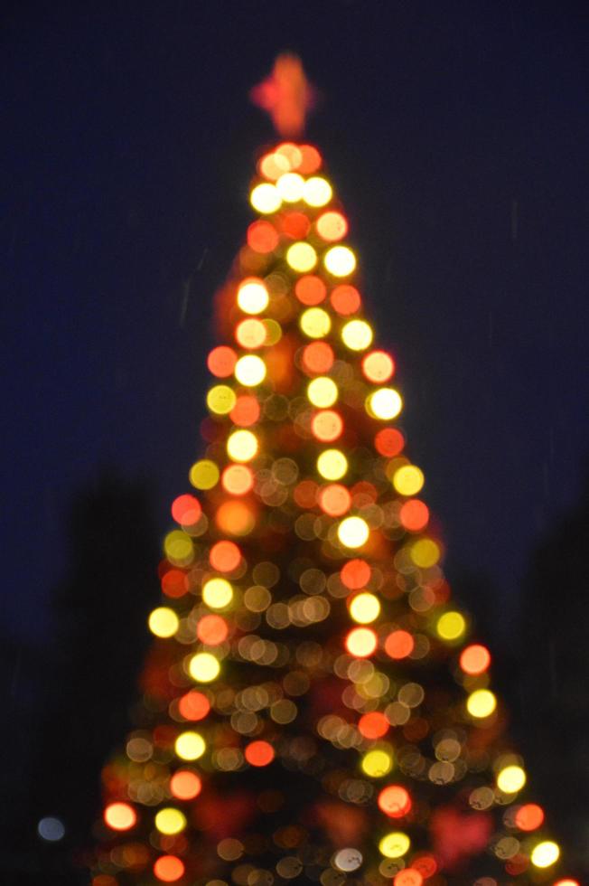 la sera e la notte l'albero di natale si illumina con le luci della città in inverno sfocate foto