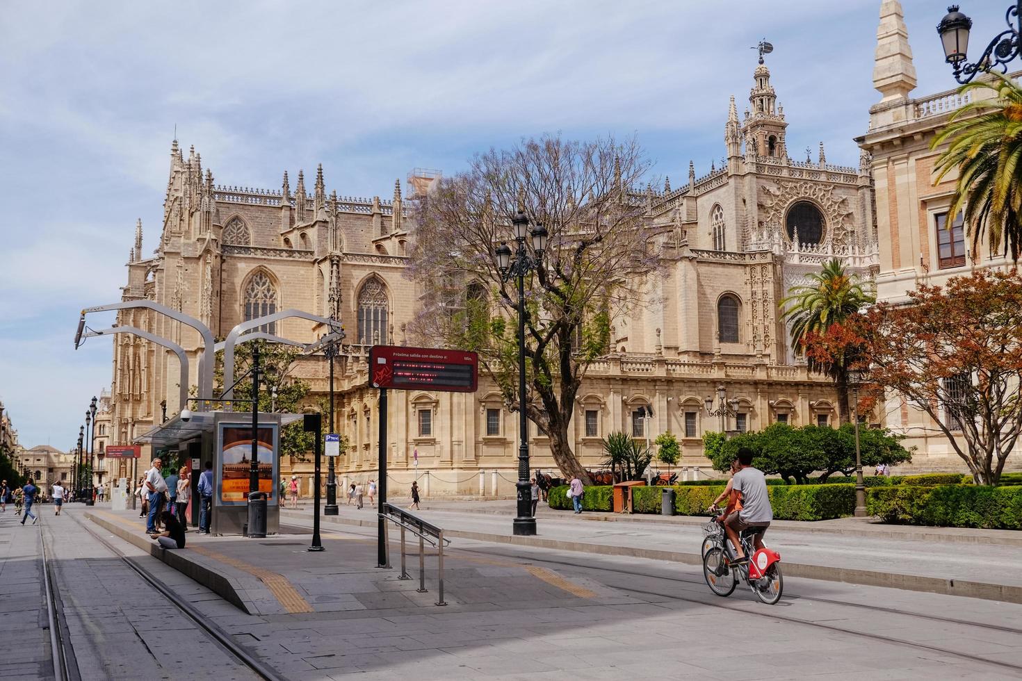 siviglia, spagna, 2017 - persone in bicicletta vicino a una fermata del tram di fronte alla cattedrale di siviglia. foto