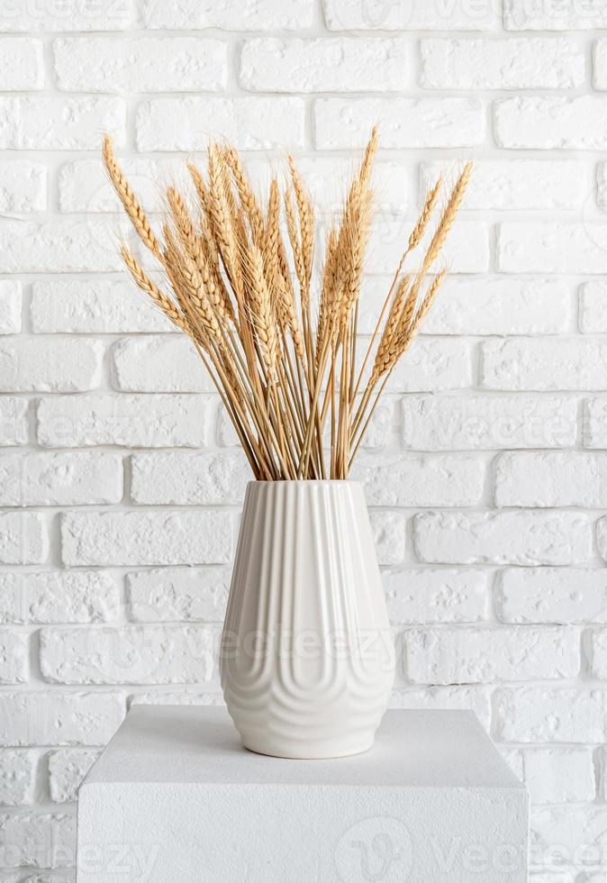 spighe di grano in un vaso bianco su sfondo bianco muro di mattoni foto