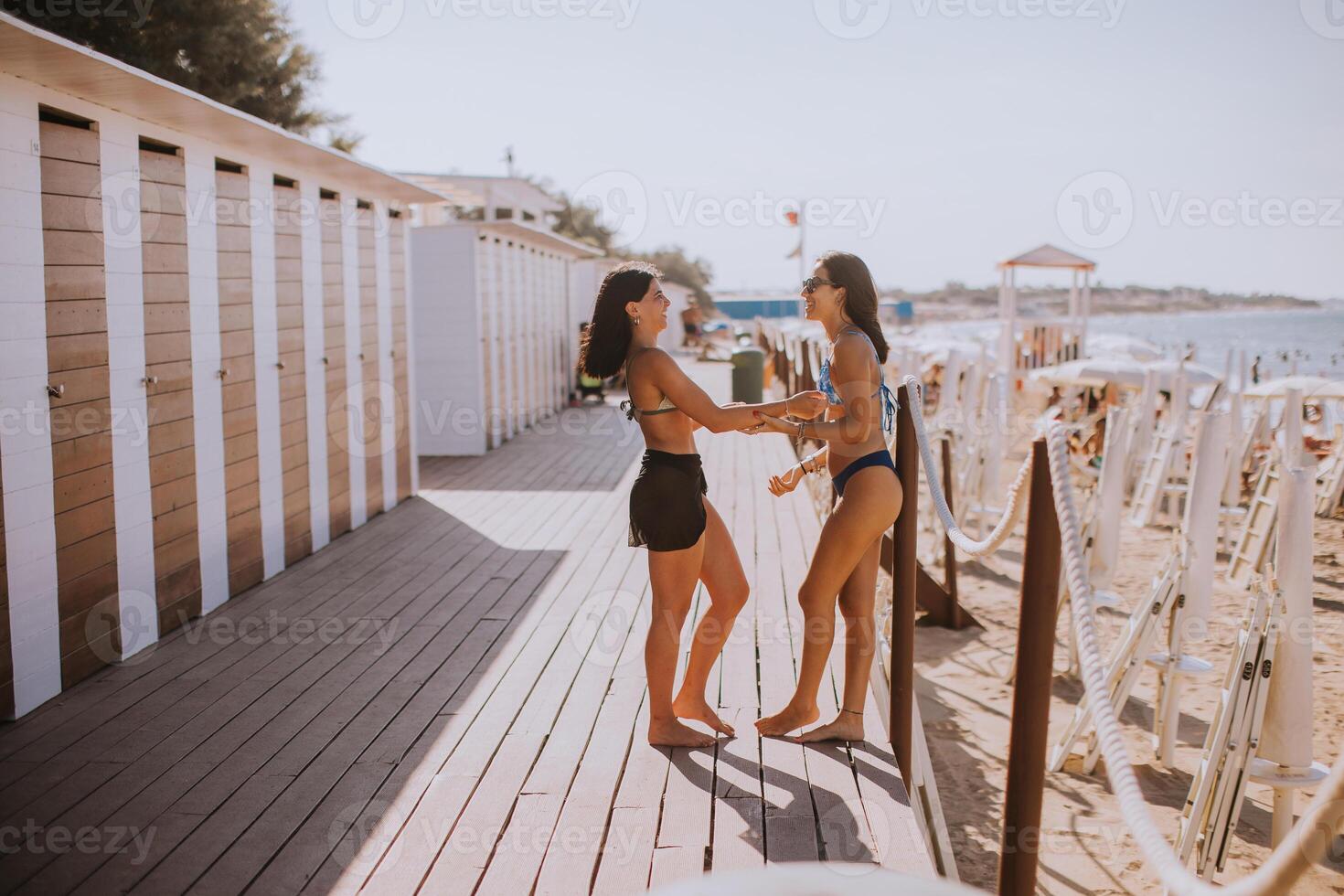 sorridente giovane donne nel bikini godendo vacanza su il spiaggia foto