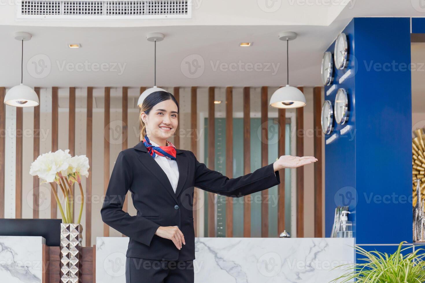 giovane donna addetto alla reception in piedi e sorridente a il davanti scrivania di il Hotel ricezione, ritratto di femmina addetto alla reception Lavorando nel Hotel foto
