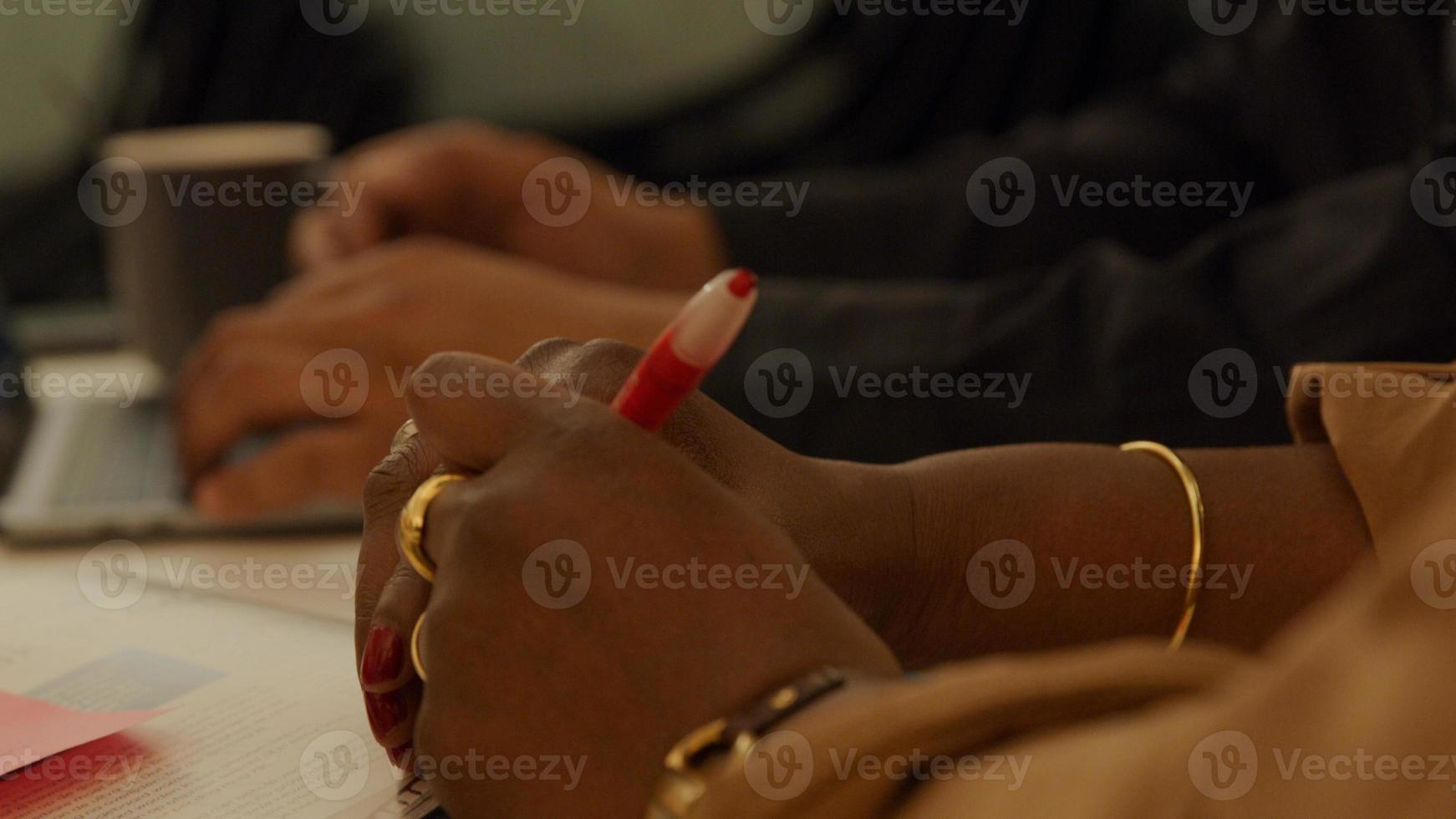 stretta di mano sul tavolo della donna matura nera, tenendo la penna foto