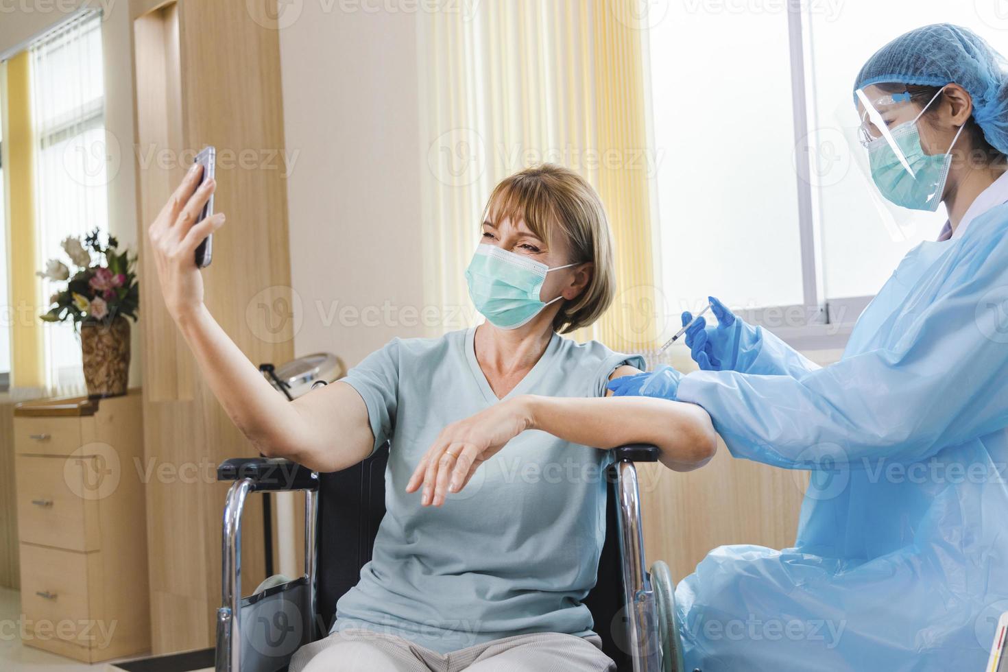 paziente anziana che riceve il vaccino contro il covid-19 o il coronavirus su una sedia a rotelle foto