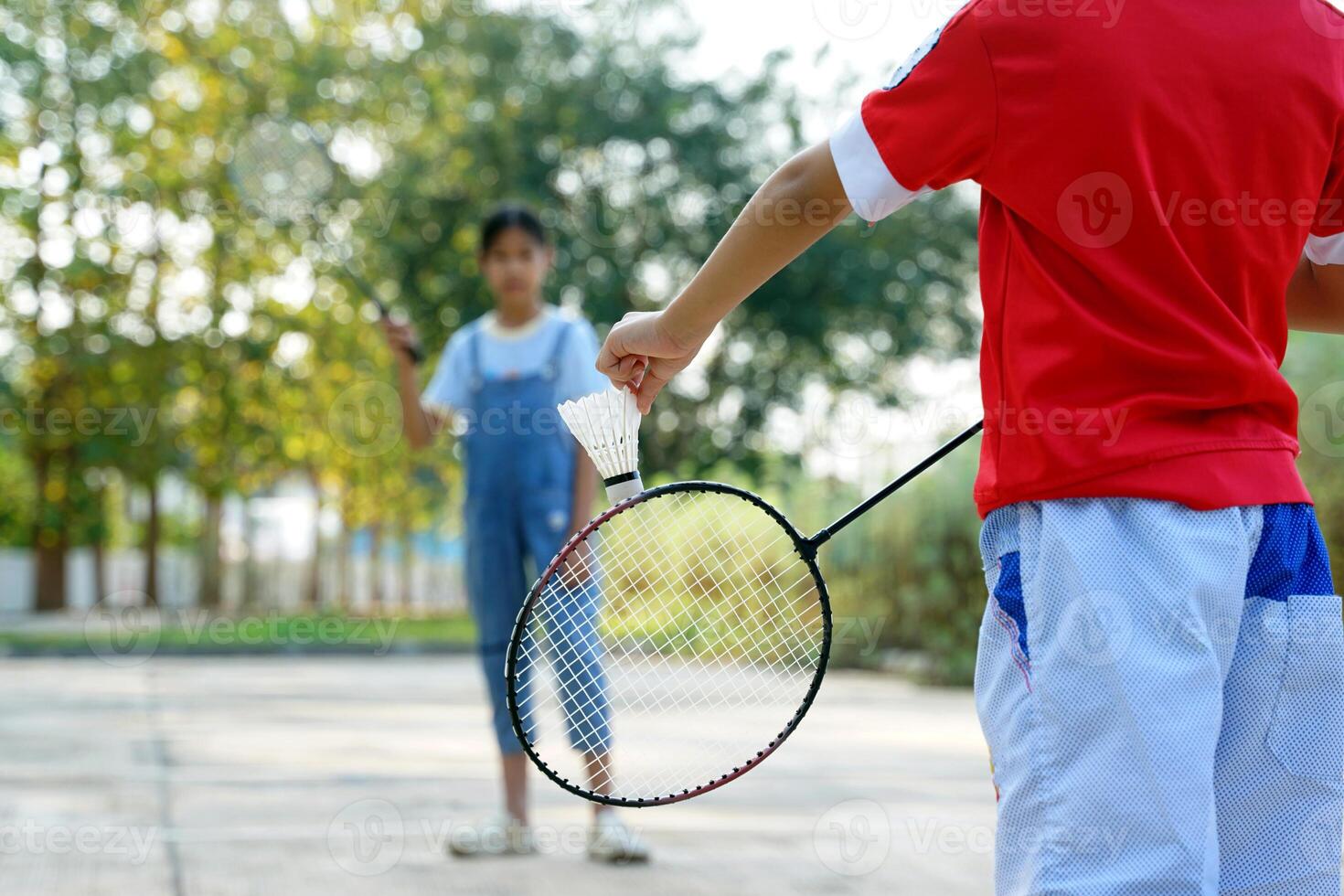 asiatico ragazza e ragazzo giocare badminton all'aperto a il parco insieme su vacanza. morbido e selettivo messa a fuoco. foto