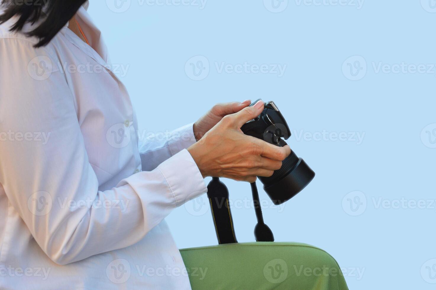 un' femmina fotografo nel un' bianca camicia su un' blu sfondo detiene un' digitale telecamera nel sua mani e visualizzazioni sua opera. foto