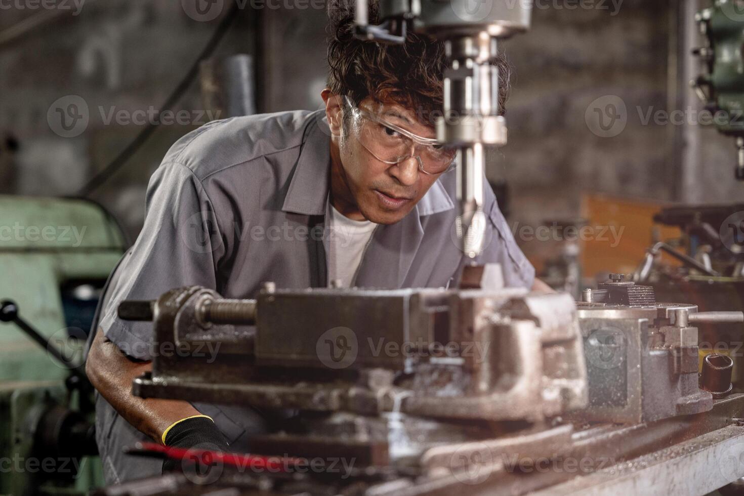 ingegnere lavoratore nel produzione pianta perforazione a macchina. professionale lavoratore vicino perforazione macchina su fabbrica. uomo ispezionando e riparazione macchina per operazione nel officina. foto