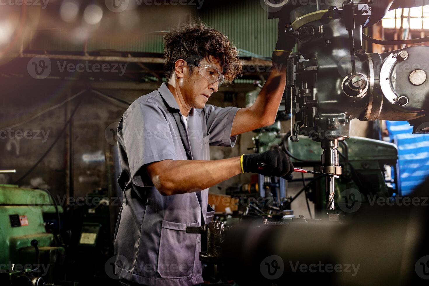 ingegnere lavoratore nel produzione pianta perforazione a macchina. professionale lavoratore vicino perforazione macchina su fabbrica. uomo ispezionando e riparazione macchina per operazione nel officina. foto