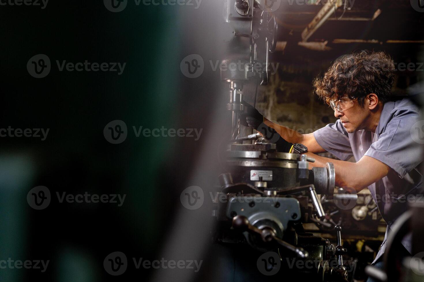 asiatico lavoratore nel produzione pianta perforazione a macchina. professionale lavoratore vicino perforazione macchina su fabbrica. finitura metallo Lavorando interno acciaio superficie su tornio macinino macchina con volante scintille. foto