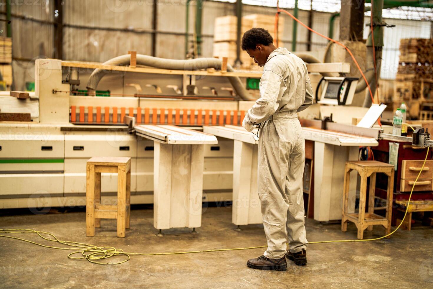 africano uomo lavoratori ingegneria in piedi con fiducia con Lavorando suite vestito e mano guanto nel davanti macchina. concetto di inteligente industria lavoratore operativo. legna fabbrica produrre legna palato. foto