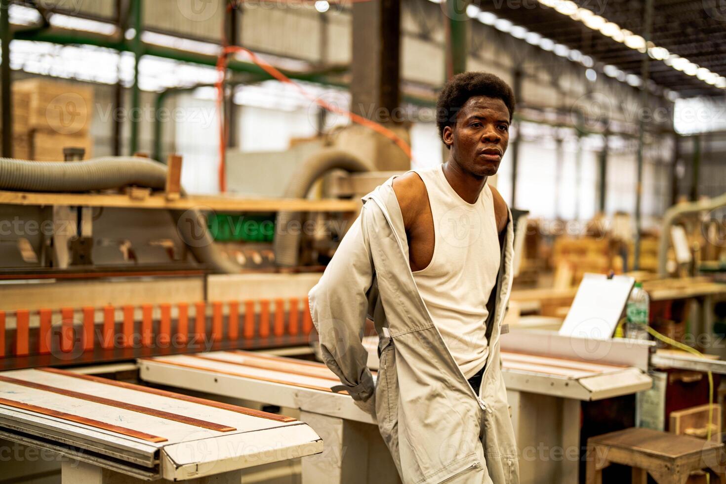 africano uomo lavoratori ingegneria in piedi con fiducia con Lavorando suite vestito e mano guanto nel davanti macchina. concetto di inteligente industria lavoratore operativo. legna fabbrica produrre legna palato. foto