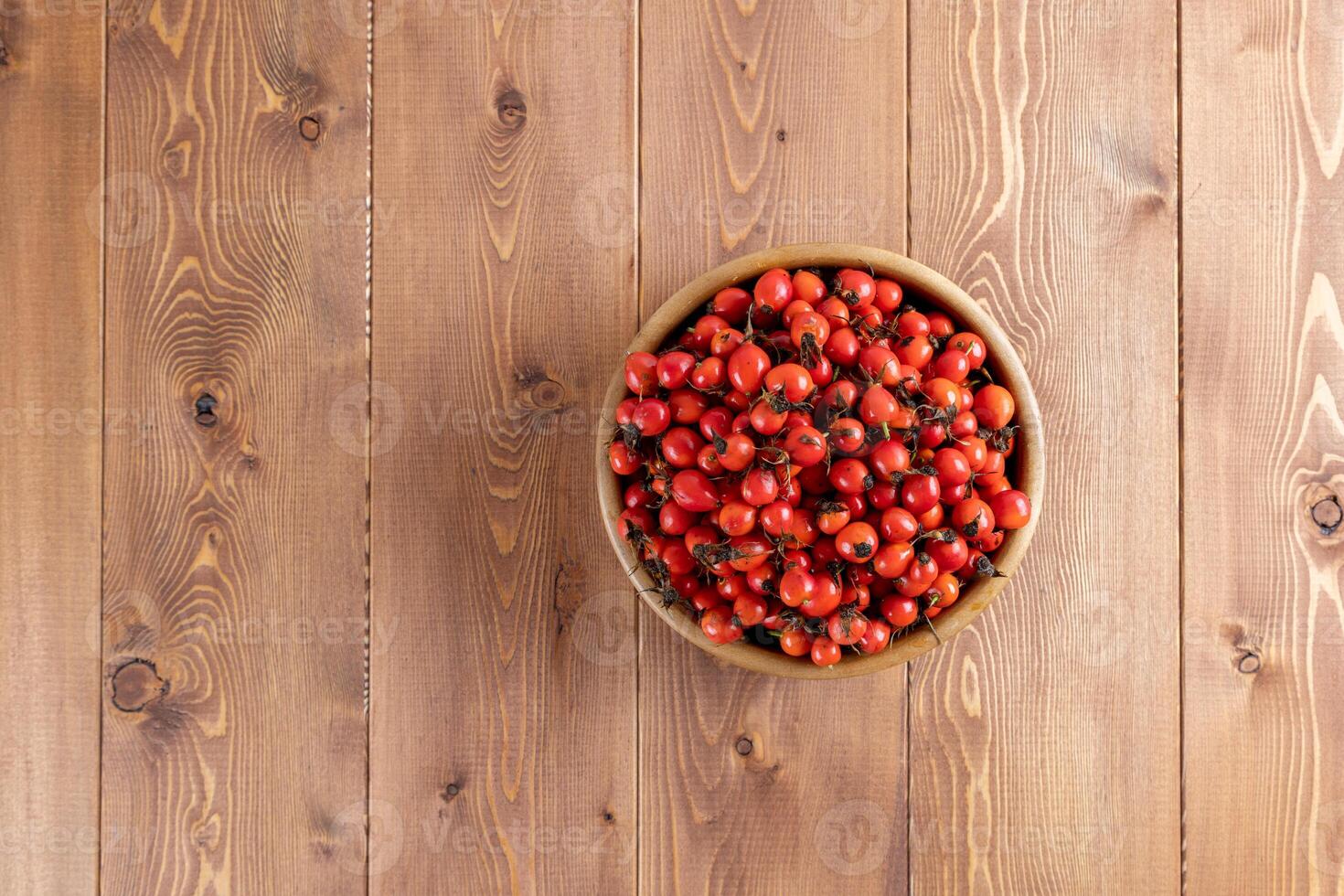 rosso rosa canina rosa canina frutta nel un' di legno ciotola su di legno tavolo foto