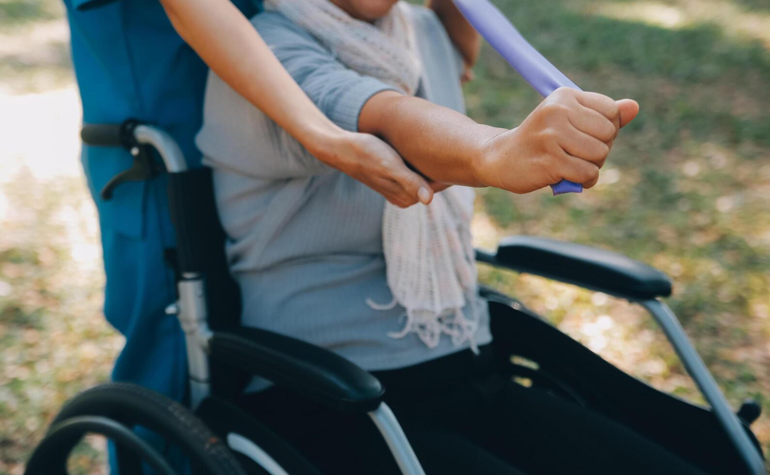 giovane infermiera o fisioterapista nel scrub porzione un' contento pensionato vecchio donna fare fitness esercizi con leggero peso manubri a casa. concetto di fisioterapia per gli anziani foto