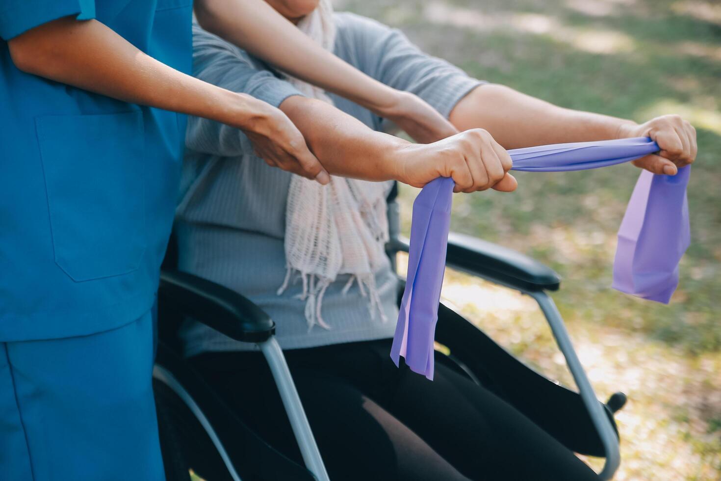 giovane infermiera o fisioterapista nel scrub porzione un' contento pensionato vecchio donna fare fitness esercizi con leggero peso manubri a casa. concetto di fisioterapia per gli anziani foto