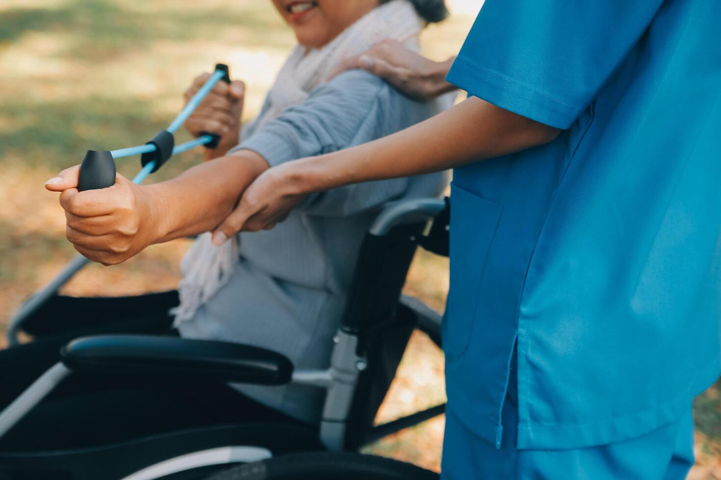 giovane infermiera o fisioterapista nel scrub porzione un' contento pensionato vecchio donna fare fitness esercizi con leggero peso manubri a casa. concetto di fisioterapia per gli anziani foto