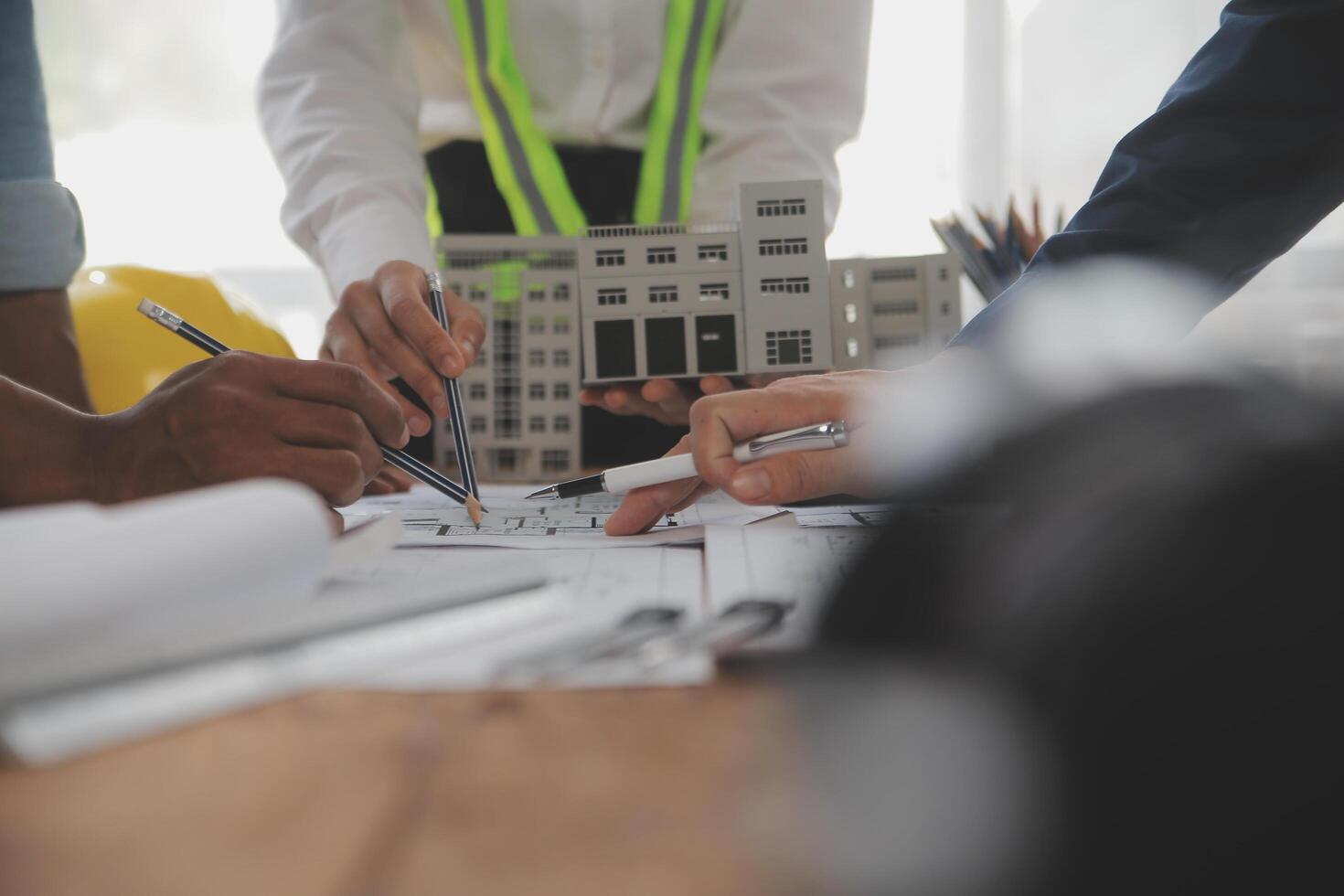 costruzione e struttura concetto di ingegnere o architetto incontro per progetto Lavorando con compagno e ingegneria utensili su modello edificio e planimetria nel Lavorando luogo, contrarre per tutti e due aziende. foto