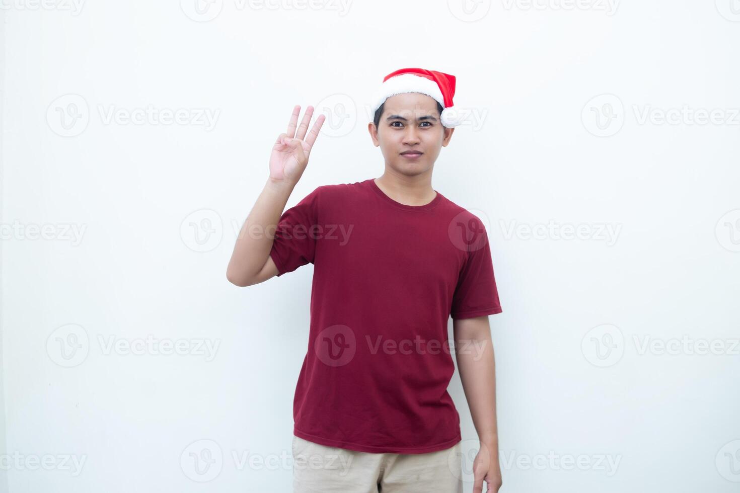 giovane asiatico uomo indossare un' Santa Claus cappello sorridente, shock e puntamento per sua lato isolato di bianca sfondo per visivo comunicazione foto