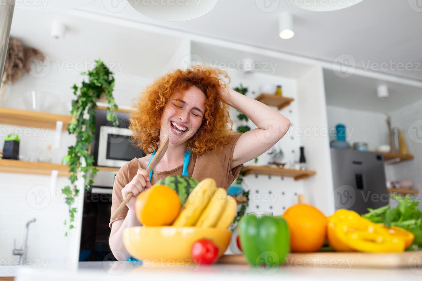 divertente bellissimo donna cantando in spatola, cucinando nel moderno cucina, Tenere spatola come microfono, ballare, ascoltando per musica, giocoso ragazza avendo divertimento con stoviglie, preparazione cibo. foto