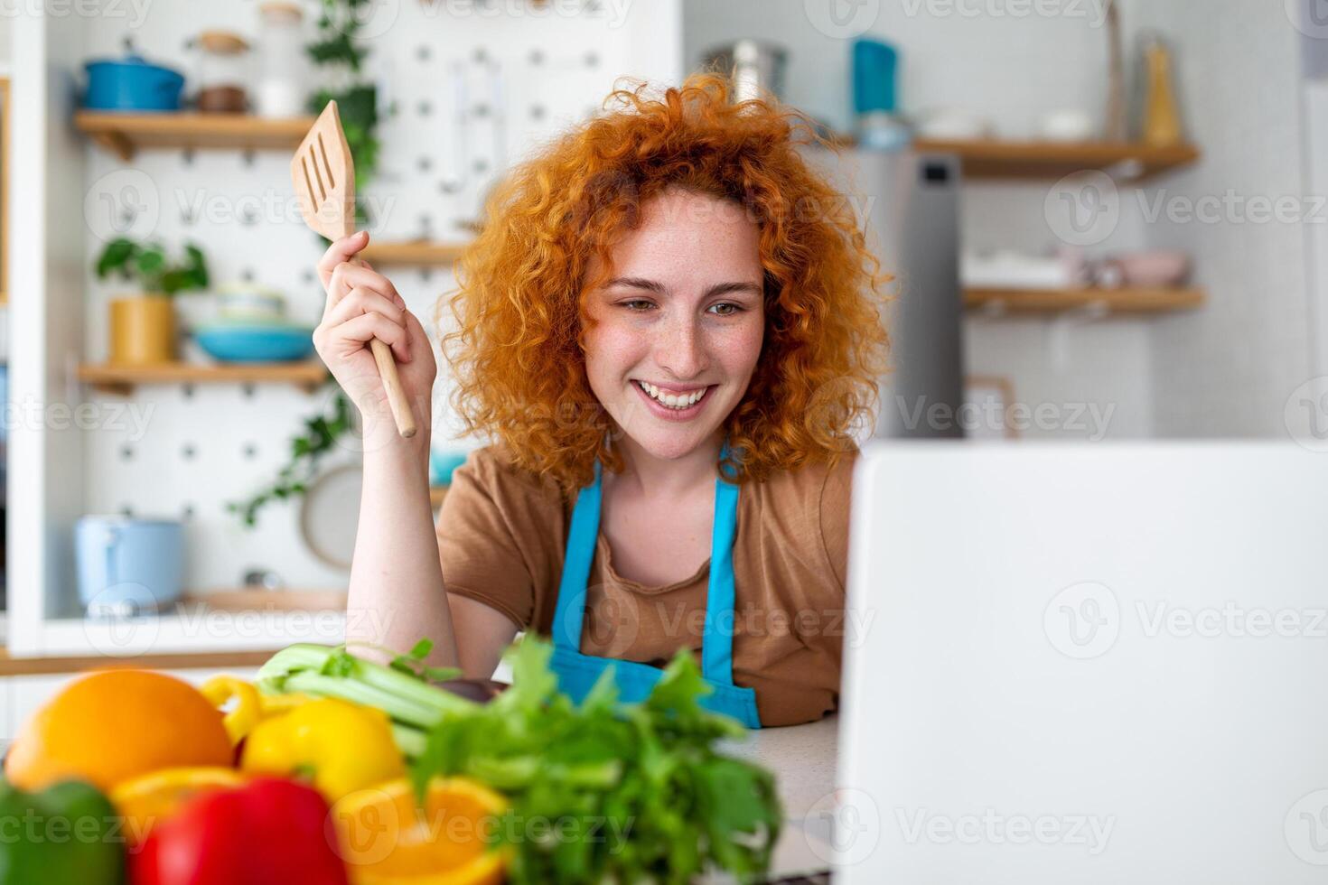 un' giovane donna impara per cucinare, lei orologi video ricette su un' il computer portatile nel il cucina e cucinare un' piatto . cucinando a casa concetto foto