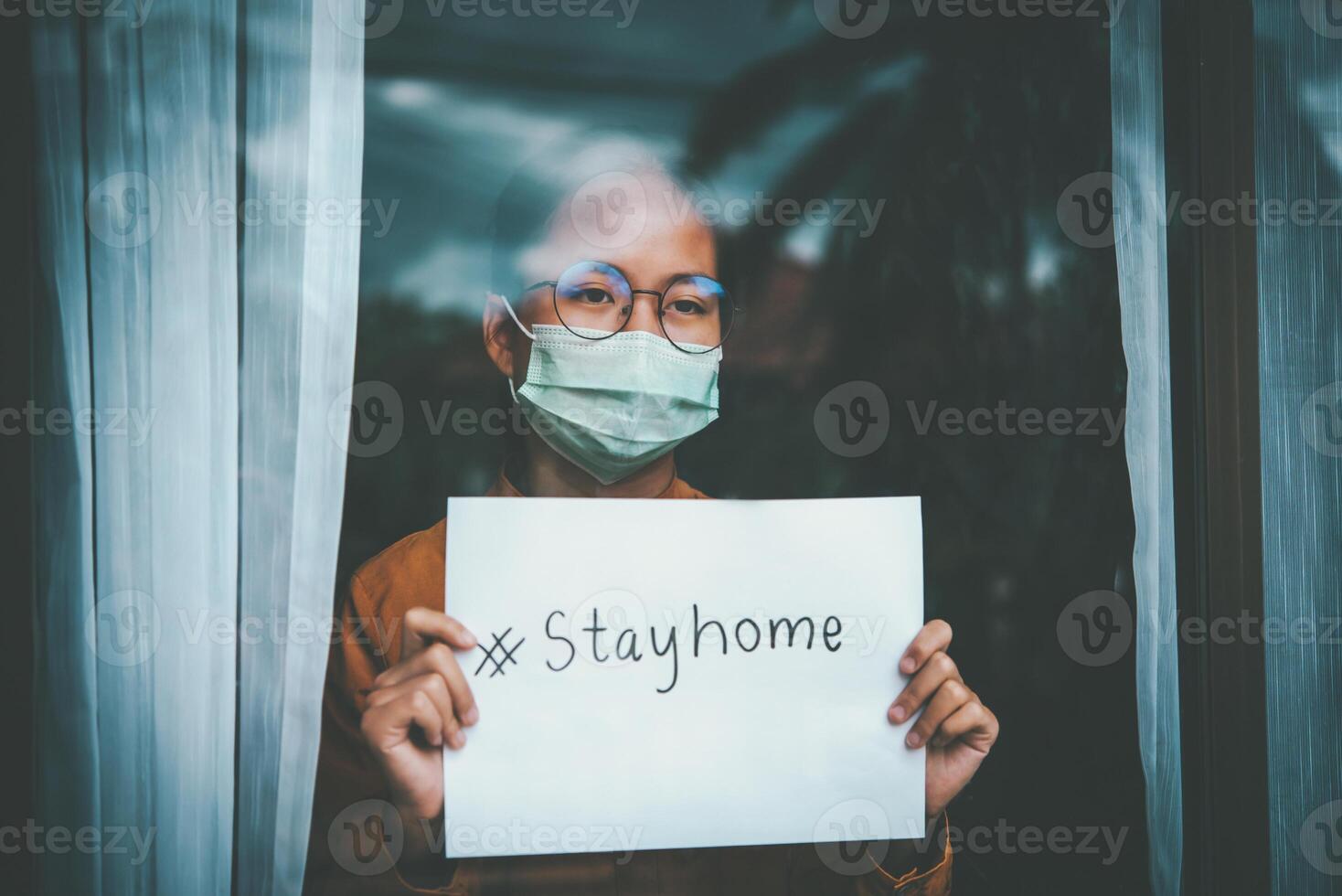 asiatico ragazza indossare occhiali, indossare un' maschera, Tenere carta etichettato stare a casa, è annoiato di avendo per trattenere e trattare il malattia a casa solo. concetto casa quarantena, prevenzione covid-19 foto