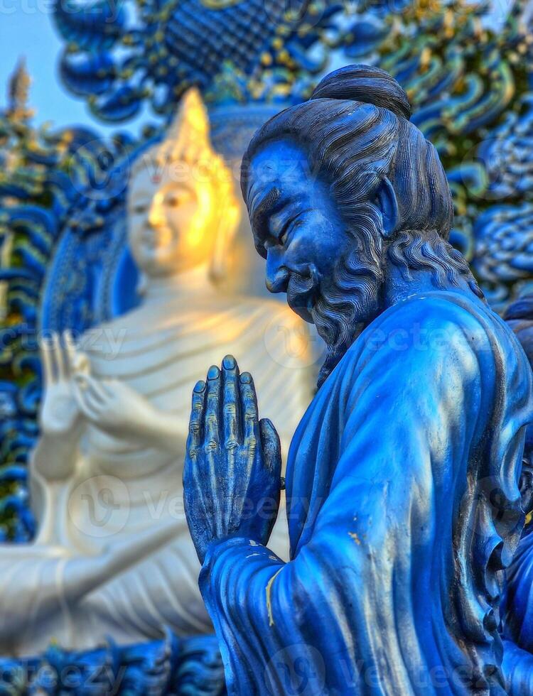 preghiere monaco statua a wat rong suaa dieci blu tempio, chiang rai, Tailandia foto