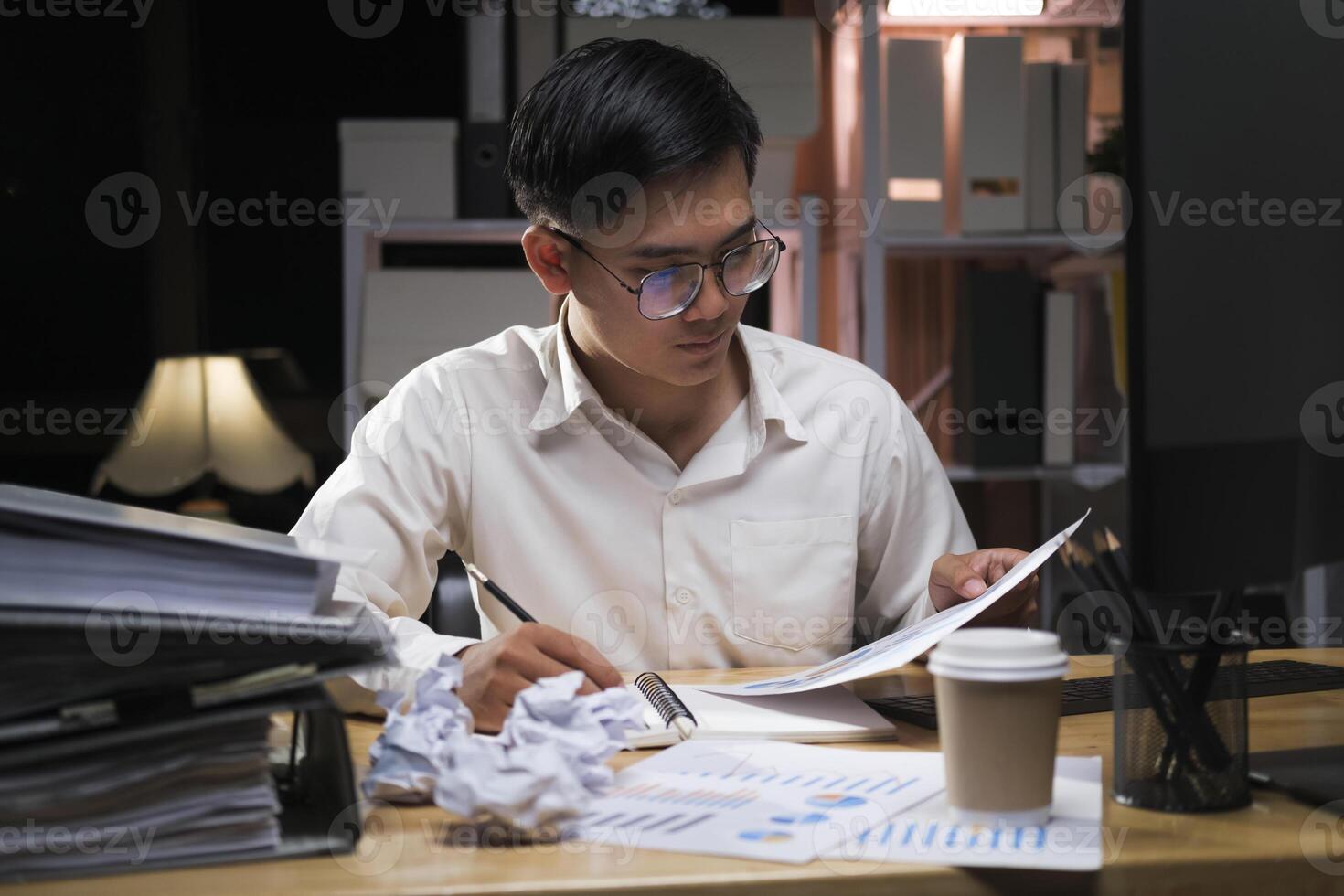 giovane uomo d'affari Lavorando col tempo su un' scrivania a notte. foto