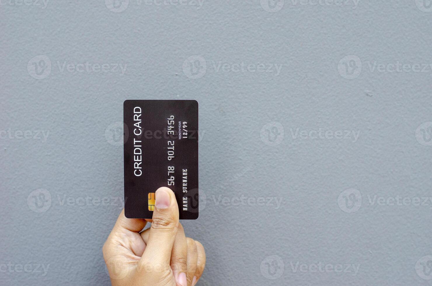 femmina mano Tenere un' nero credito carta modello con sicurezza patata fritta incorporato su un' grigio sfondo con copia spazio foto