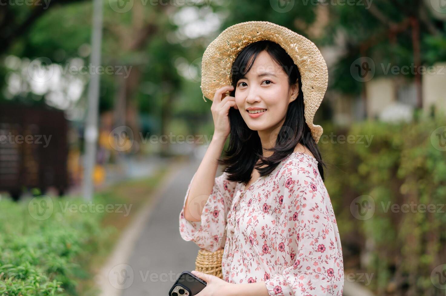 ritratto di asiatico giovane donna viaggiatore con tessitura cappello e cestino contento Sorridi su verde pubblico parco natura sfondo. viaggio viaggio stile di vita, mondo viaggio esploratore o Asia estate turismo concetto. foto