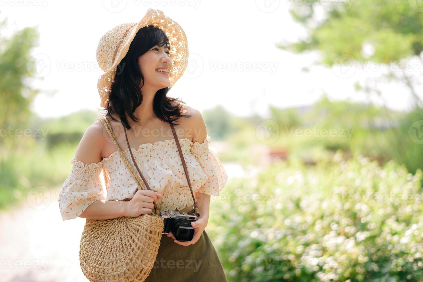 ritratto di asiatico giovane donna viaggiatore con tessitura cappello e cestino e un' telecamera su verde pubblico parco natura sfondo. viaggio viaggio stile di vita, mondo viaggio esploratore o Asia estate turismo concetto. foto