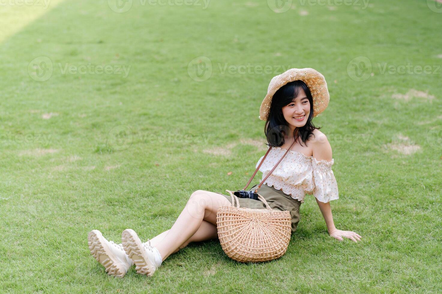 ritratto di asiatico giovane donna viaggiatore con tessitura cappello e cestino e un' telecamera su verde pubblico parco natura sfondo. viaggio viaggio stile di vita, mondo viaggio esploratore o Asia estate turismo concetto. foto