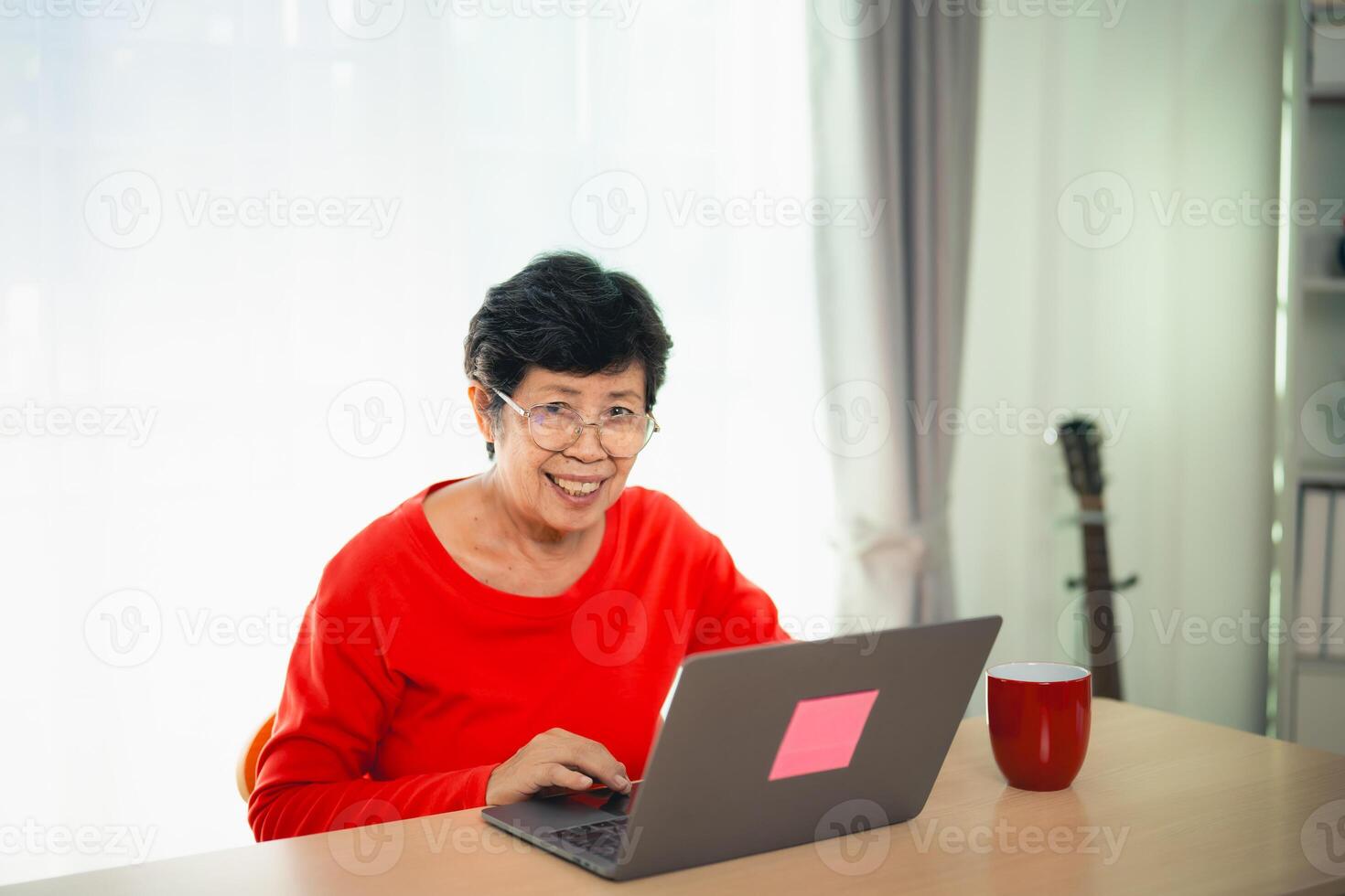 anziano vecchio asiatico donna Lavorando dopo la pensione utilizzando il computer portatile a casa. vecchio libero professionista Lavorando o apprendimento nuovo tecnologia su il computer portatile nel vivente camera. la pensione attività concetto. foto
