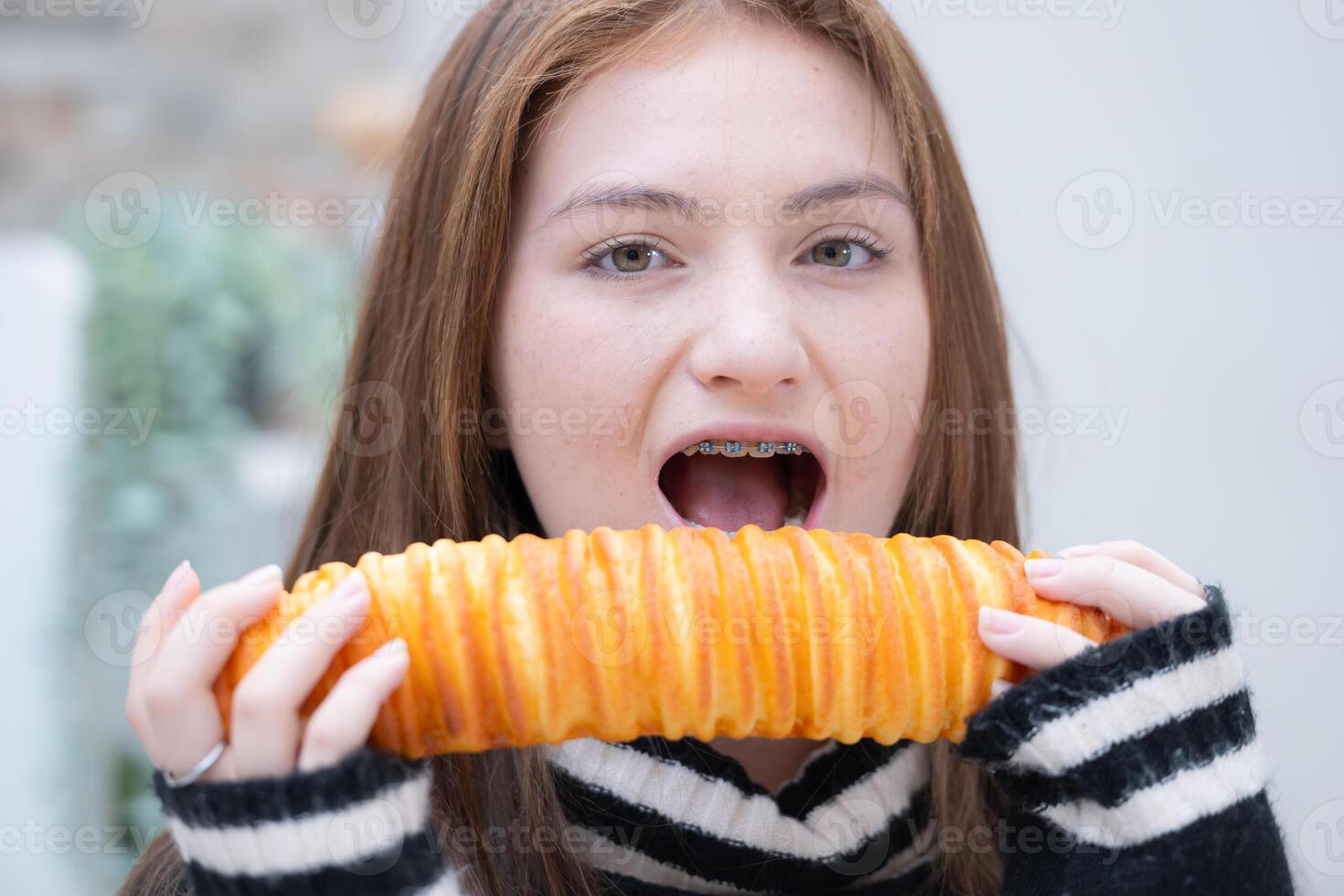 ritratto di adolescenziale ragazza mangiare pane nel il cucina a casa foto