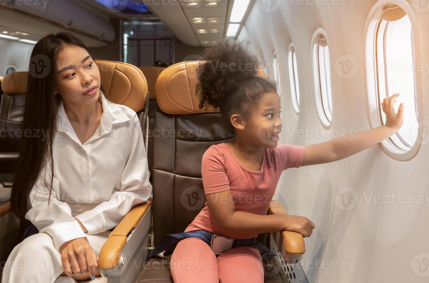 contento madre e figlia seduta su aereo posto a sedere e guardare a aereo finestra. foto