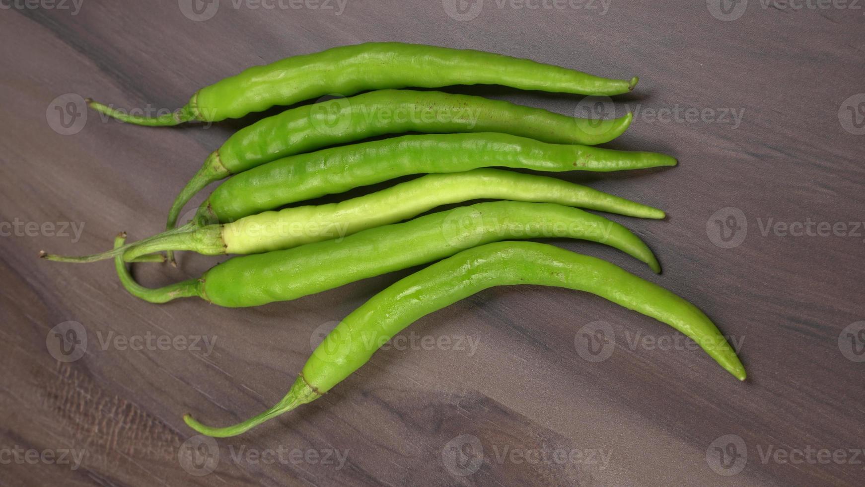 peperoncini verdi indiani lunghi freschi su fondo di legno. foto