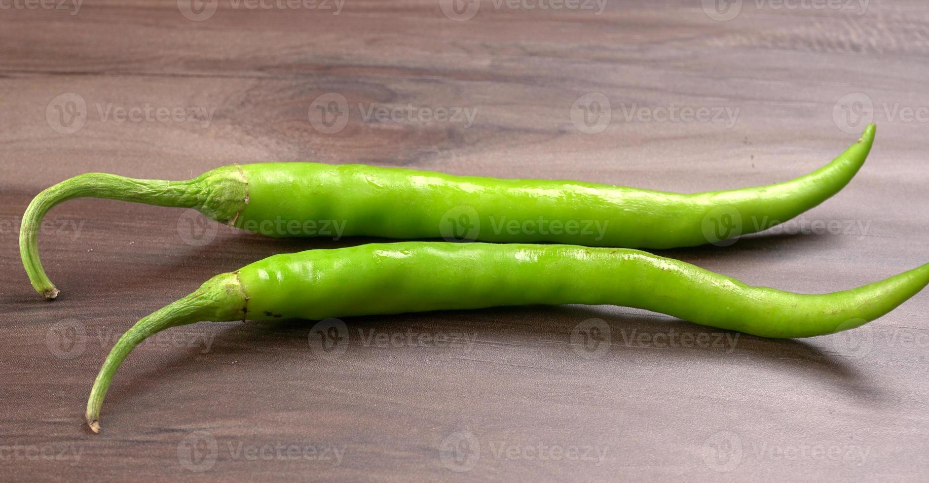 peperoncini verdi indiani lunghi freschi su fondo di legno. foto