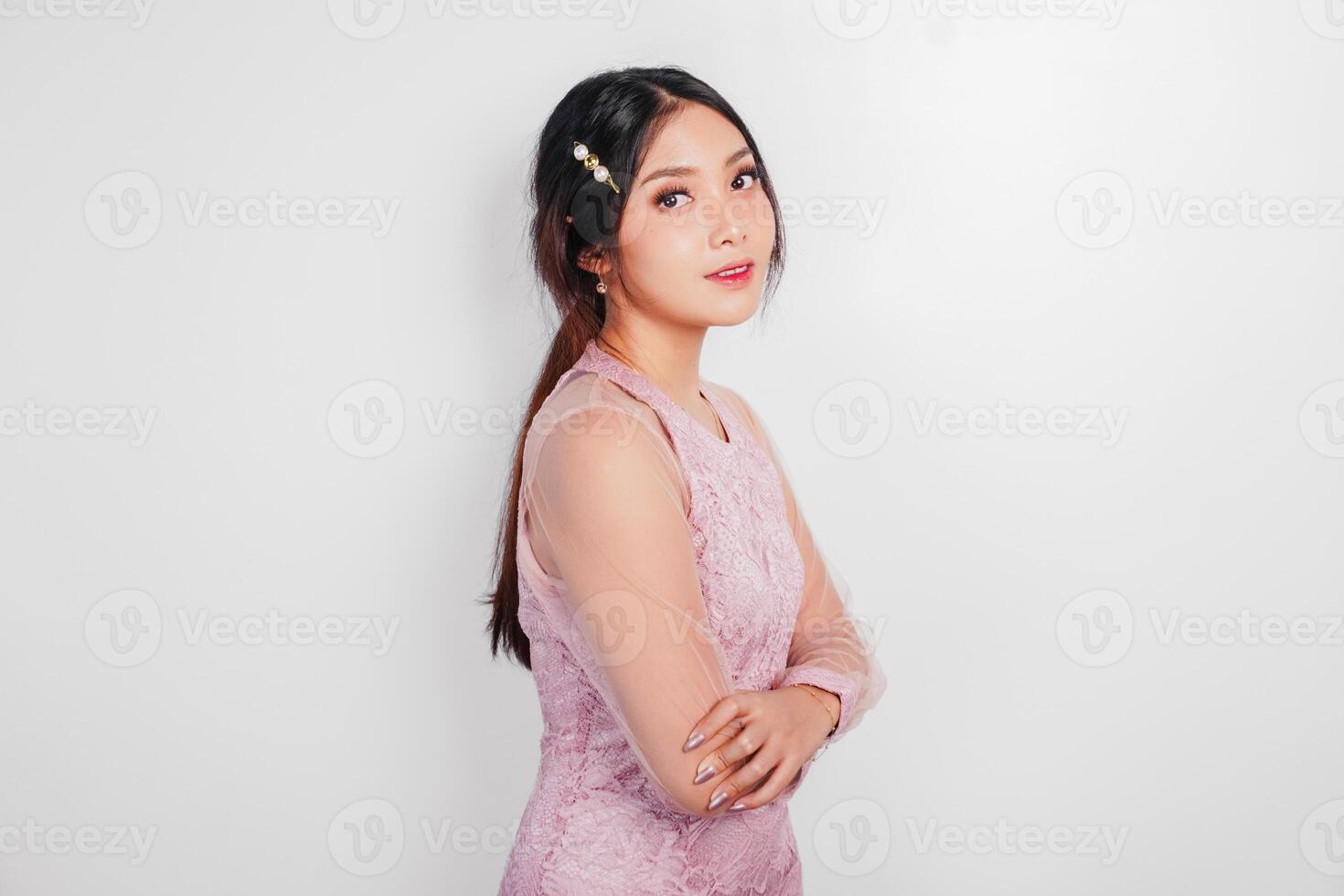 un attraente asiatico donna indossare rosa vestito è sorridente per il telecamera, isolato di bianca sfondo. foto