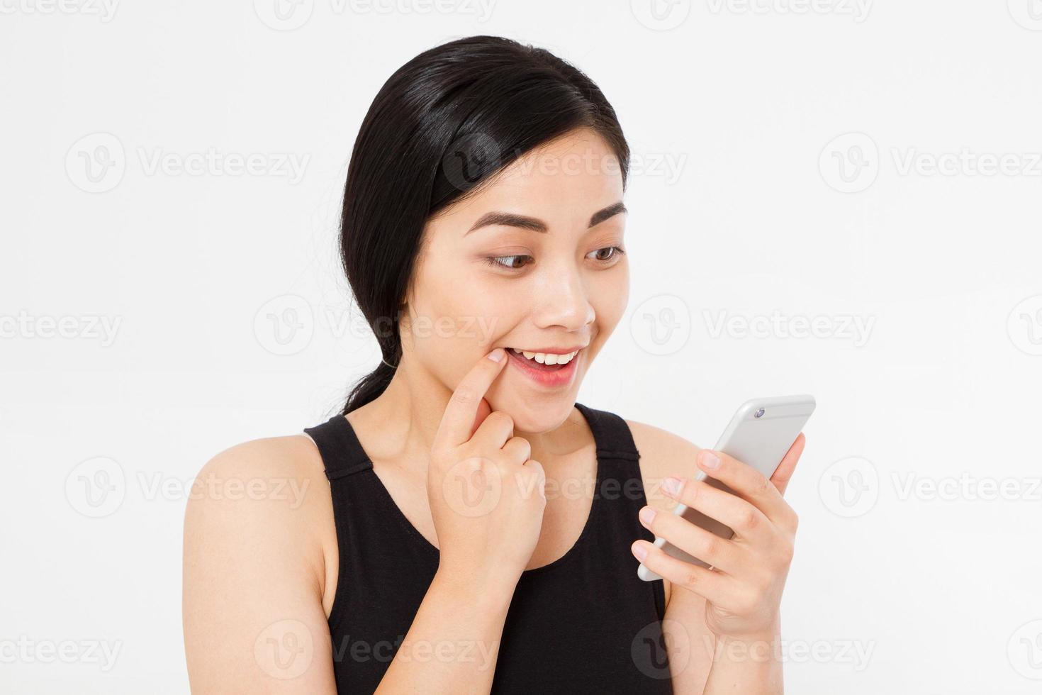 cellulare sorridente della stretta della donna. primo piano giovane bella donna giapponese asiatica felice. ragazza guardando cellulare mobile isolato su sfondo bianco. espressione positiva del viso emozione umana. copia spazio. foto