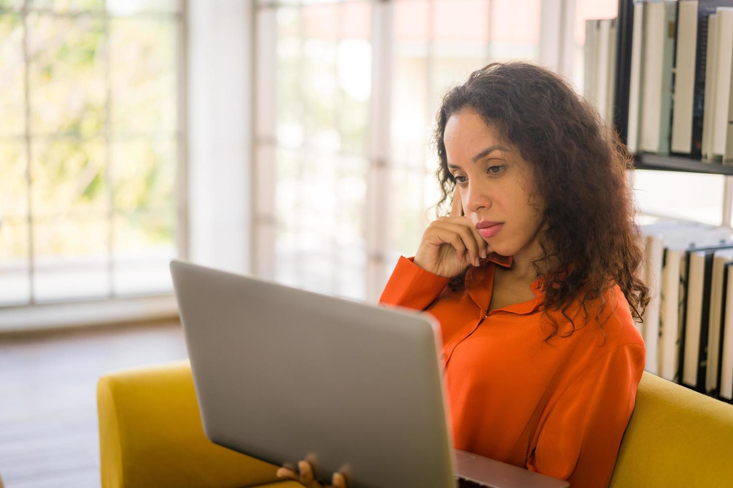 donna latina che lavora con il laptop sul divano con sensazione di stanchezza foto