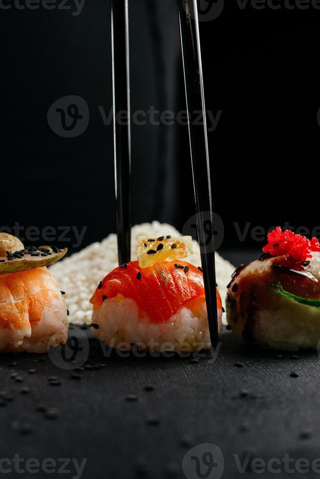 mano Tenere bastoncini un' elegante pezzo di Sushi a ristorante. California rotolo Sushi giapponese cibo riso sfera. davanti Visualizza. creativo giapponese cucina concetto. alto qualità foto