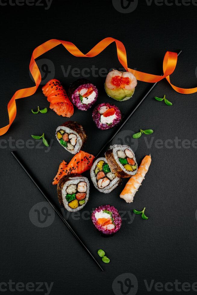 Sushi impostato con caviale, avocado e salmone. Sushi pezzi posto fra bacchette, separato su nero sfondo. asiatico cucina. superiore Visualizza. gratuito spazio per il tuo testo. alto qualità foto