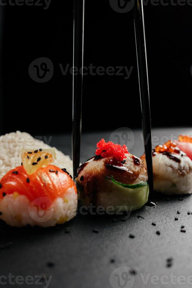 Sushi impostato con caviale, avocado e salmone. Sushi pezzi posto fra bacchette, separato su nero sfondo. asiatico cucina. superiore Visualizza. gratuito spazio per il tuo testo. alto qualità foto