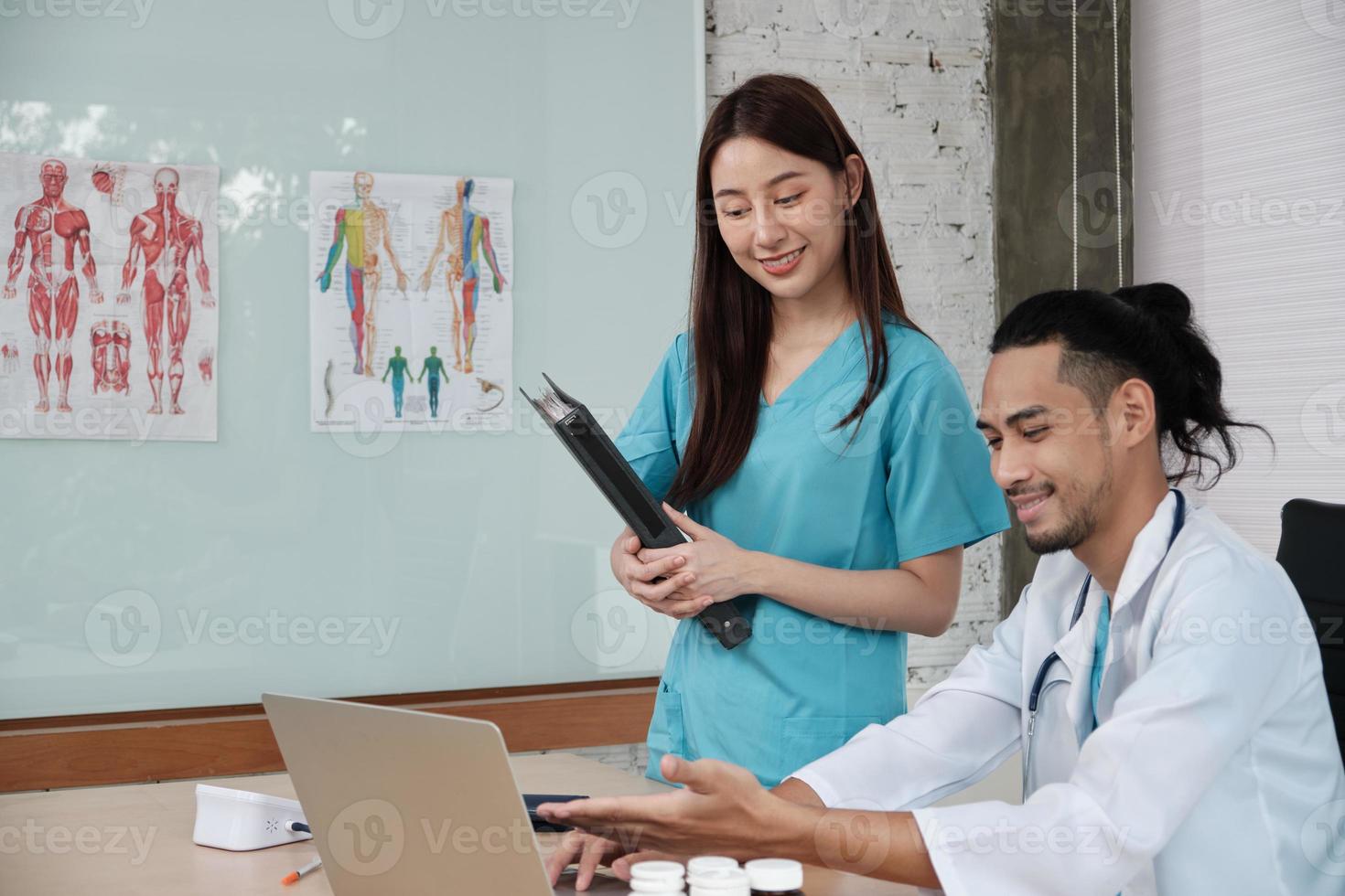 partner del team sanitario. due giovani medici di etnia asiatica in uniforme sono colleghi che discutono di farmaci nell'ufficio della clinica dell'ospedale. le persone specializzate sono esperti e professionisti. foto